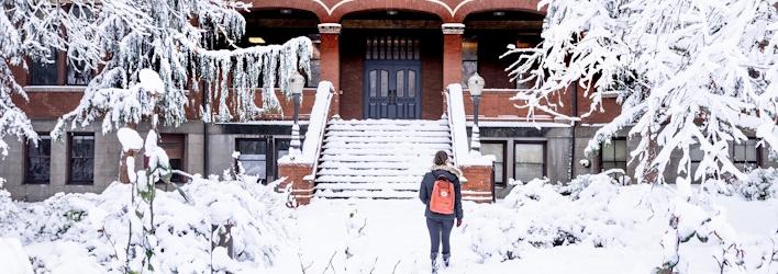 A student walks up to a snowy Peterson hall